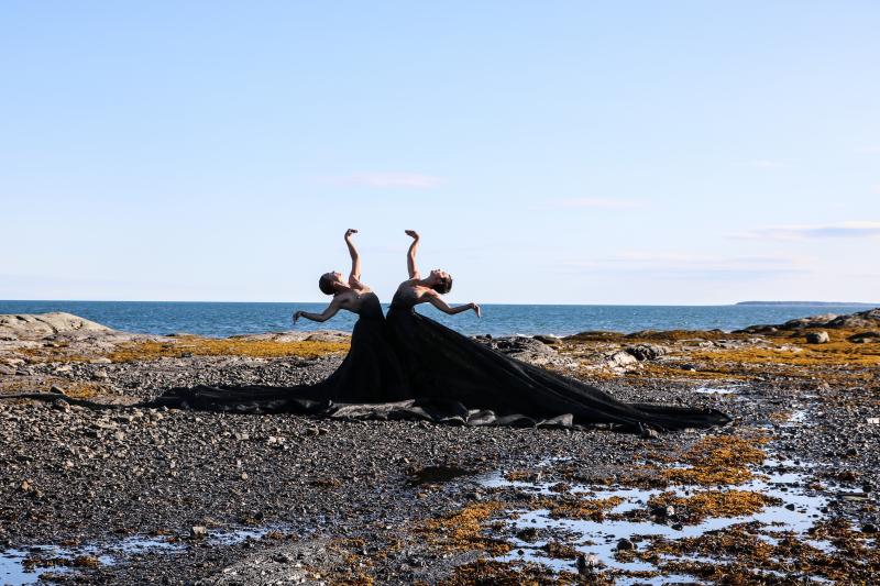 Danseuses sur le littoral avec vue sur un plan d'eau à l'arrière.
