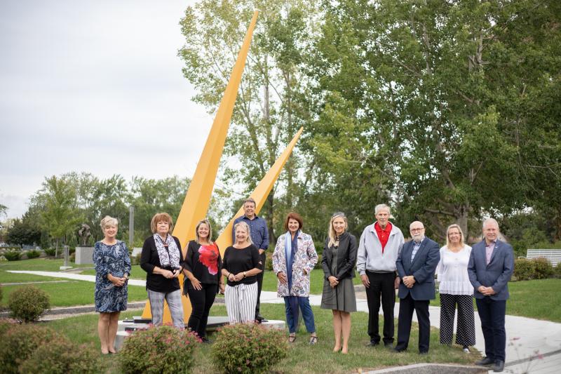 Sont devant la sculpture Le Temps s’est arrêté, les conseillers municipaux : Cécile Hénault, Denyse Peltier, Chantal Routhier, Josée Mailhot, Jean Langlois, la mairesse de la Ville de Repentigny, Chantal Deschamps, la fille de Lewis Pagé, Anne-Marie Simard Pagé, les conseillers municipaux : Raymond Hénault, Georges Robinson et Éric Chartré et la vice-présidente du Club Lions Repentigny la Seigneurie, Dominique Michaud.