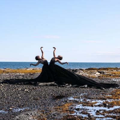 Danseuses sur le littoral avec vue sur un plan d'eau à l'arrière.